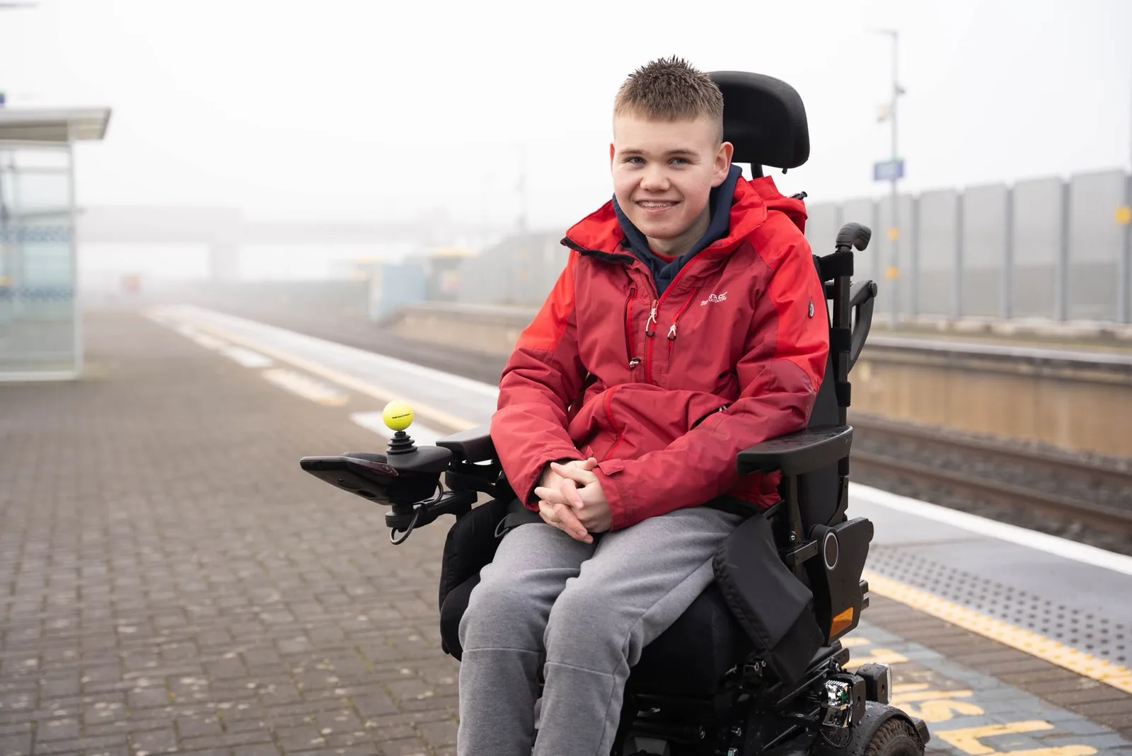 James waiting at a train station platform in his wheelchair